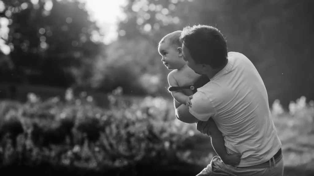 Little daughter looks over father's shoulder while he holds her